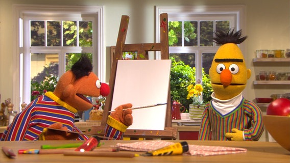 Ernie steht links vor einer Staffelei mit Pinsel in der Hand und Bert steht rechts daneben © NDR Foto: Screenshot